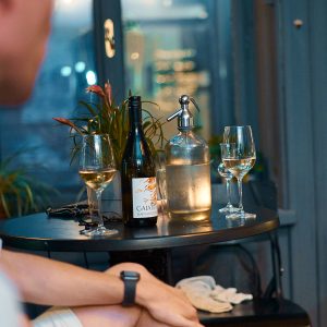 bottle of wine, bottle of soda, and wine and pálinka glasses on table