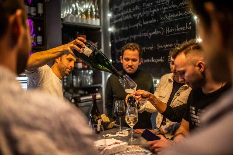 bartender pouring wine for guest at bar