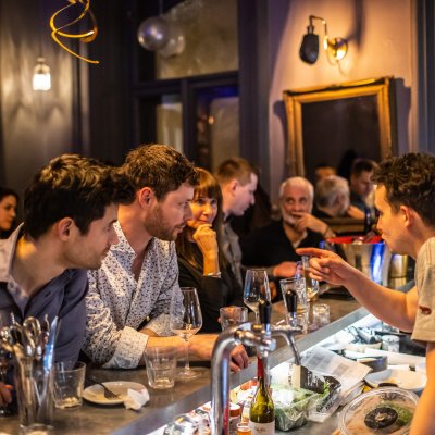 customers huddled in at the bar chatting with the bartender